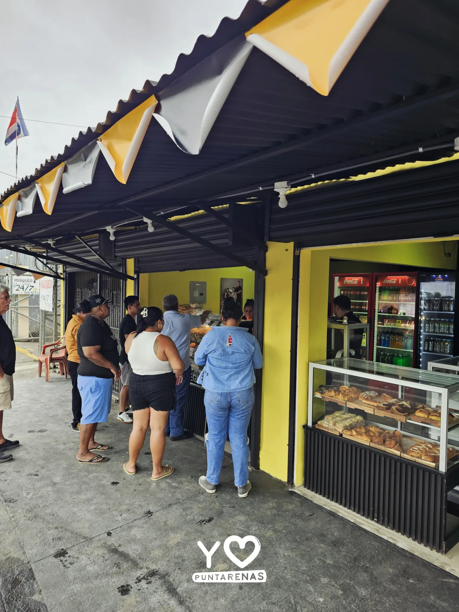 Vista lateral del toldo de Pasteles y empanadas donde Lore, con clientes siendo atendidos.